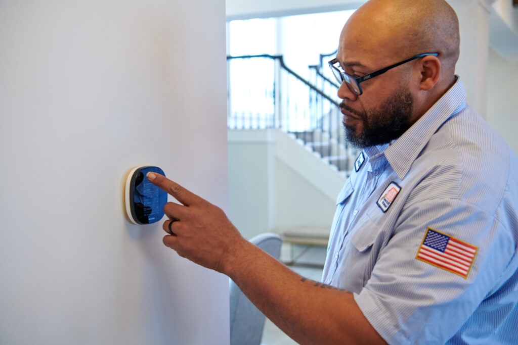 AC tech adjusting a thermostat