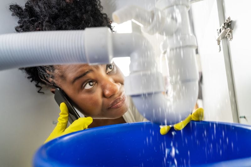 How to Prevent Frozen or Burst Pipes This Winter - Woman Fixing Burst Pipe.