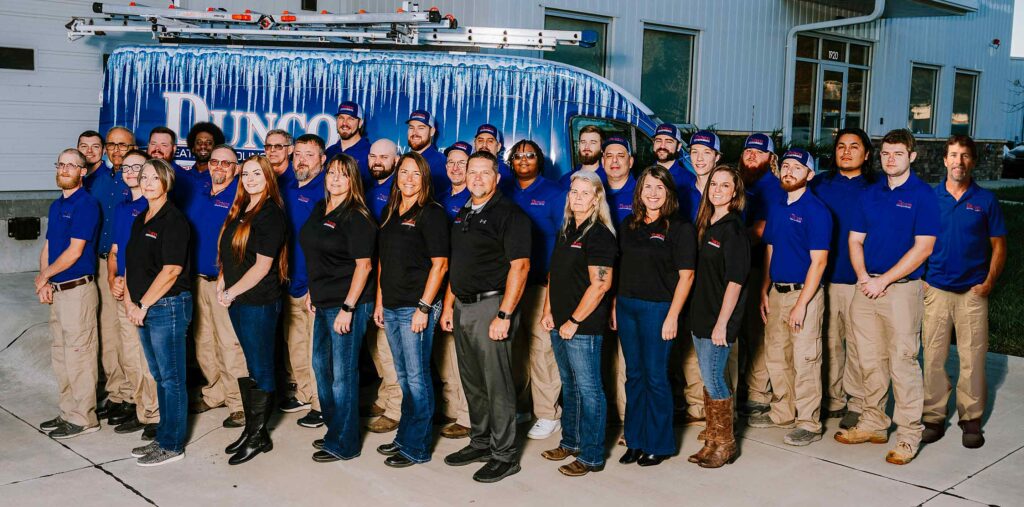 Image of the entire Dunco Heating and Cooling team in front of their work vans